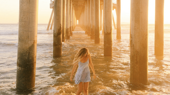 woman standing in water under a pier
