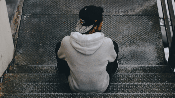 man with backwards cap sitting on staircase
