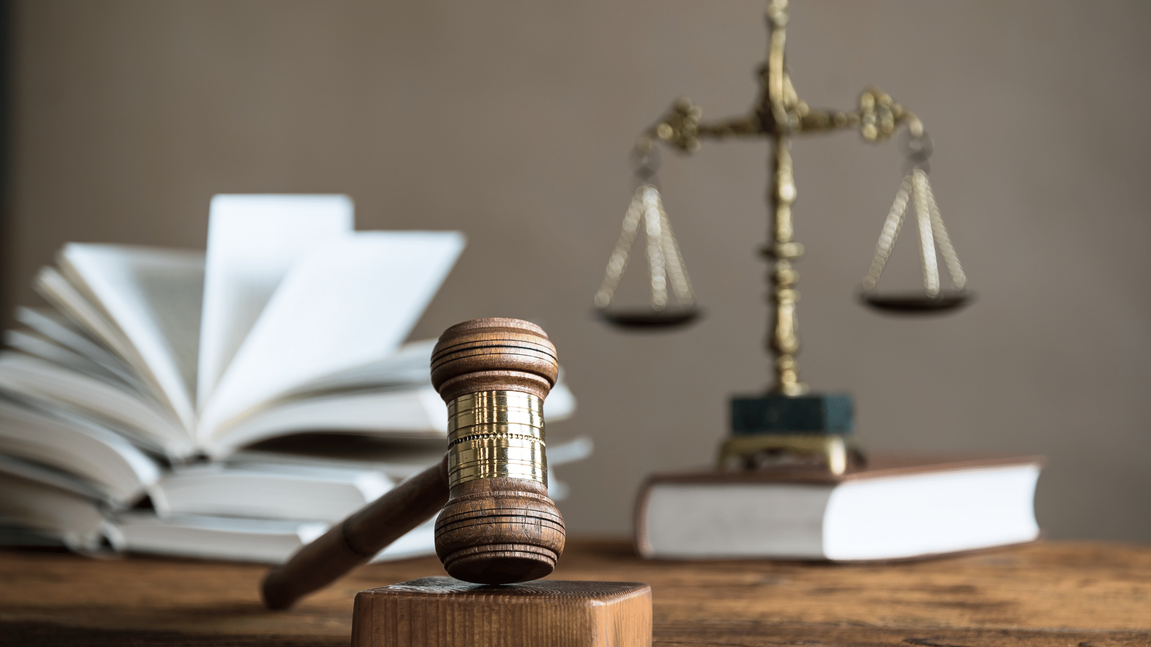 A judge’s gavel on a wooden block with law books and scales of justice in the background.